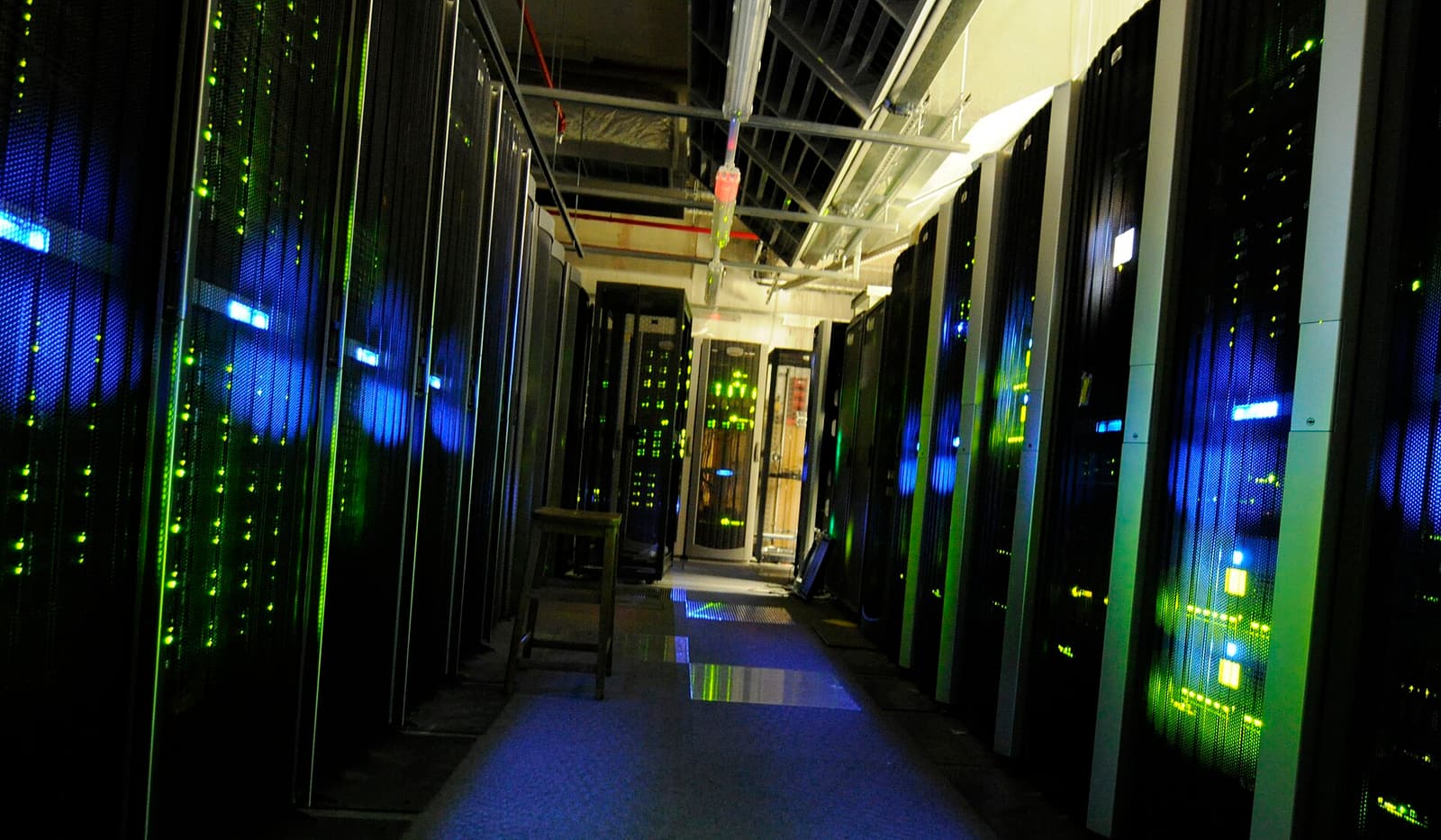 An aisle of servers lit in blue and green