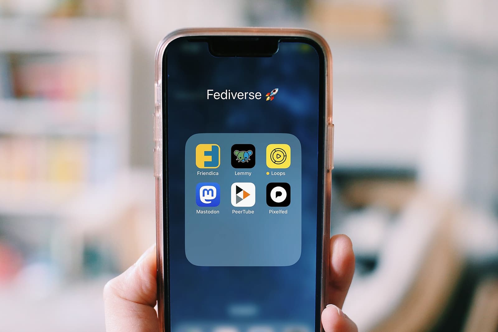 Hand holding a smartphone showing a folder of apps