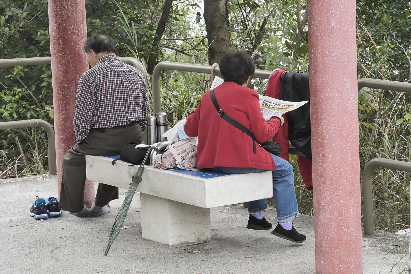 Two older people sitting in a park pavilion
