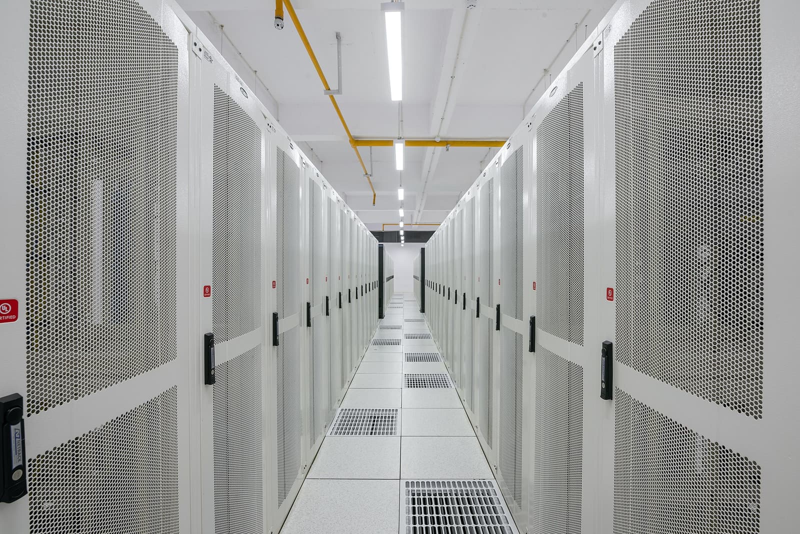 A white aisle of server racks in a data centre